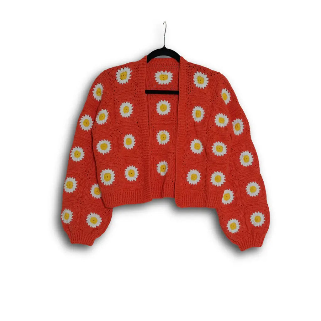 Red sweater with white daisy patterns on a hanger against a white background