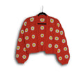 Red sweater with white daisy patterns on a hanger against a white background
