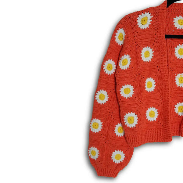 Red sweater with white daisy patterns on a white background