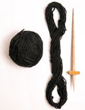 Handspun 100% pure black Himalayan wool yarn hank and ball with traditional wooden spindle, ethically sourced from indigenous Lahaul Valley artisans for B2B sustainable fashion.